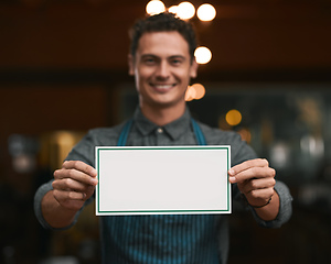 Image showing We will be glad if you can join us. Portrait of a cheerful young man holding a sign while standing inside of a beer brewery during the day.