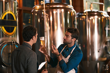 Image showing Its all about the flavor. Shot of two young working men doing inspection of their beer making machinery inside of a beer brewery during the day.