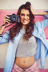 Image showing Enjoy moments and capture memories. Portrait of a beautiful young woman holding a dslr camera and posing against a wall outside.