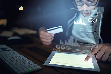 Image showing Credit card fraud - its a risk and reality. Shot of a young hacker using a digital tablet to commit credit card fraud in the dark.