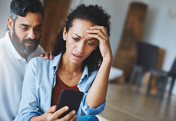 Image showing I accidentally sent that picture to your mother. Shot of a dismayed couple receiving bad news via a smartphone at home.