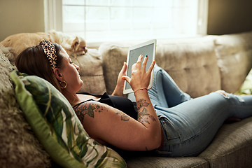 Image showing With wifi comes a lot of relaxation. Shot of a young woman using a digital tablet on the sofa at home.