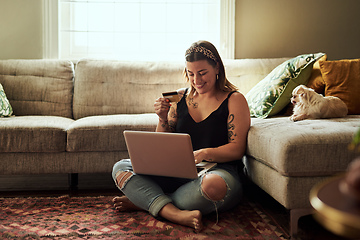 Image showing Less queues more relaxing. Shot of a young woman using a laptop and credit card in her living room at home.