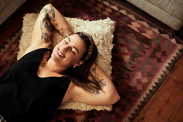 Image showing Rest your way to happiness. Shot of a young woman relaxing on the floor of her living room at home.