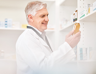 Image showing Medical, product and a senior man in a pharmacy looking for prescription medicine on a shelf. Bottle, healthcare or trust with a happy pharmacist in a drugstore for chronic medication inventory