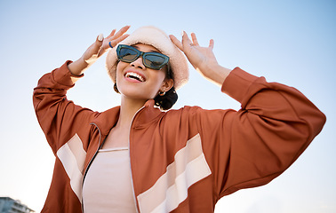 Image showing Fashion, sunglasses and smile with a trendy woman outdoor on a blue sky for freedom, energy or style. Portrait, summer and clothes with a happy young model in an urban outfit while on vacation