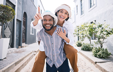 Image showing Happy interracial couple, travel or piggyback in city on romantic date to play a fun outdoor game. Smile, pointing or excited black man carrying gen z woman or walking for urban sightseeing together