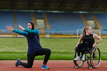 Image showing Two strong and inspiring women, one a Muslim wearing a burka and the other in a wheelchair stretching and preparing their bodies for a marathon race on the track