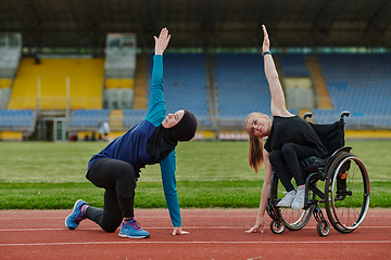 Image showing Two strong and inspiring women, one a Muslim wearing a burka and the other in a wheelchair stretching and preparing their bodies for a marathon race on the track