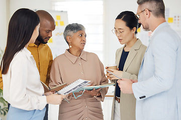 Image showing Tablet, collaboration and documents with a business team talking in the office during a meeting. Technology, paper and serious with a manager coaching a designer group in a professional workplace