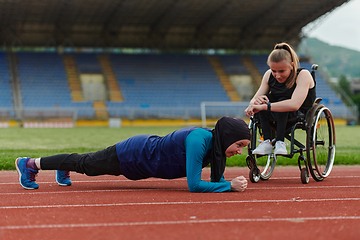 Image showing Two strong and inspiring women, one a Muslim wearing a burka and the other in a wheelchair stretching and preparing their bodies for a marathon race on the track