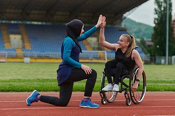 Image showing Two strong and inspiring women, one a Muslim wearing a burka and the other in a wheelchair stretching and preparing their bodies for a marathon race on the track