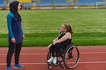 Image showing A Muslim woman wearing a burqa resting with a woman with disability after a hard training session on the marathon course