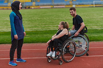 Image showing A woman with a disability in a wheelchair talking after training with a woman wearing a hijab and a man in a wheelchair