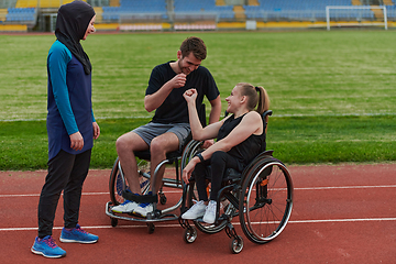 Image showing A woman with a disability in a wheelchair talking after training with a woman wearing a hijab and a man in a wheelchair