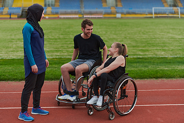 Image showing A woman with a disability in a wheelchair talking after training with a woman wearing a hijab and a man in a wheelchair