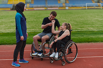 Image showing A woman with a disability in a wheelchair talking after training with a woman wearing a hijab and a man in a wheelchair