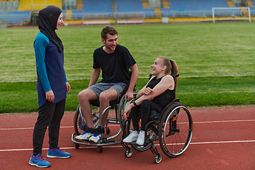 Image showing A woman with a disability in a wheelchair talking after training with a woman wearing a hijab and a man in a wheelchair