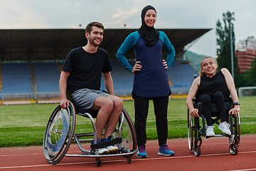 Image showing A woman with a disability in a wheelchair talking after training with a woman wearing a hijab and a man in a wheelchair