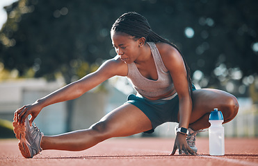 Image showing Exercise, sports and a woman stretching outdoor on a track for running, training or workout. African athlete person at stadium for legs stretch, fitness and muscle warm up or body wellness on ground