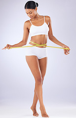 Image showing Fitness, body and progress with woman and tape in studio for weight loss, detox and workout. Wellness, diet and health with person on white background for results, cosmetics and goal measurement