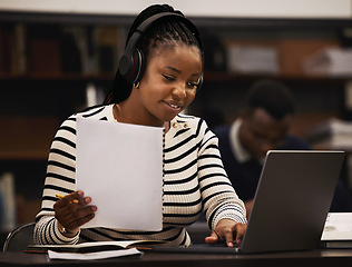 Image showing Woman, studying and headphones in library for research, documents and computer research or planning in university. African student reading paper, listening to music or laptop for focus and e learning