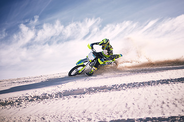 Image showing Bike, sky and speed with a man on sand riding a vehicle in the desert for adventure or adrenaline. Motorcycle, training and dust with an athlete outdoor in nature for freedom, power or competition