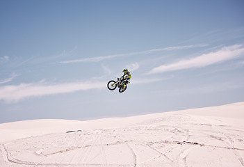 Image showing Bike, sky and jump with a man in the desert riding a vehicle for adventure or adrenaline. Motorcycle, speed and training on sand with an athlete outdoor in nature for freedom or extreme sports