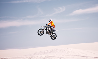 Image showing Motorcycle, sky and jump with a man in the desert riding a vehicle for adventure or adrenaline. Bike, speed and training on sand with an athlete in the air in nature for freedom or active competition