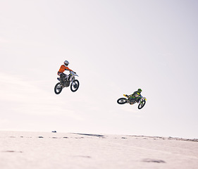 Image showing Dune, jump and men on motorbike together for practice, training and extreme sports energy in nature. Professional dirt biking challenge, friends and danger with motorcycle competition on desert hill.