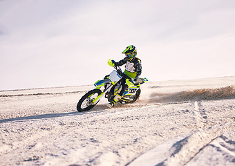 Image showing Motorcycle, dust and speed with a sports man riding a vehicle in the desert for adventure or adrenaline. Bike, freedom and training on sand with an athlete outdoor in nature for power or competition