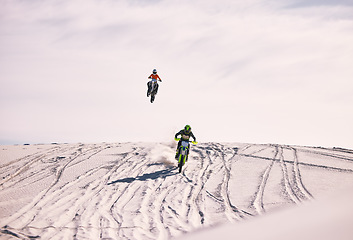 Image showing Dune, jump and men in motorbike race together for practice, training and extreme sports energy. Professional dirt biking challenge, friends and danger with off road motorcycle competition in desert.