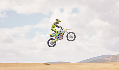 Image showing Desert, motorbike cycling and jump for sports, agile driving and off road adventure with mockup space in cloudy sky. Motorcycle, challenge and moving in air for action, fearless talent and sand dunes