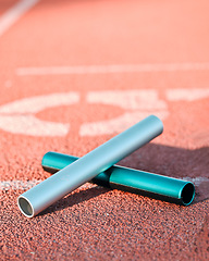 Image showing Sports, track and closeup of baton in a stadium for a relay race, marathon or competition. Fitness, running and zoom of athletic equipment on the ground for cardio training, workout or exercise.