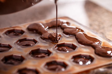 Image showing Pouring chocolate in mold