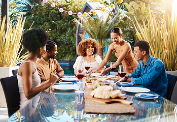 Image showing Friends, food and people outdoor at a table for social gathering, happiness and holiday celebration. Diversity, men and women group eating lunch at party or reunion with drinks to relax in a garden