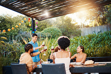 Image showing Cheers, friends at dinner in garden at party and celebration with diversity, food and wine at outdoor party. Glass toast, men and women at table, fun people with sunset drinks in backyard together.