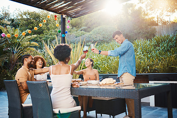 Image showing Toast, friends at dinner in garden at party and celebration with diversity, food and wine at outdoor party. Glass cheers, men and women at table, fun people with sunset drinks in backyard together.