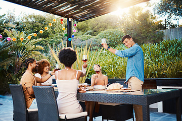 Image showing Cheers, group of friends at dinner in garden at party and celebration with diversity, food and wine at outdoor party. Glass toast, men and women at table, fun people with drinks in backyard together.