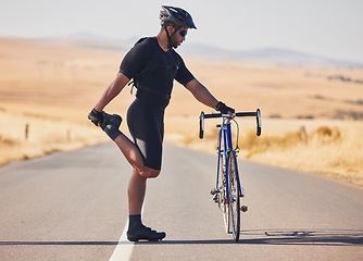 Image showing Man, cyclist and stretching on road with bicycle in fitness, training or outdoor sports in countryside. Active male person or athlete in body warm up, leg exercise or preparation in cycling or cardio