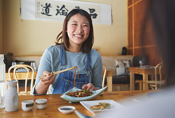 Image showing Japanese, food and woman at a restaurant eating for dinner or lunch meal using chopsticks and feeling happy with smile. Plate, date and person enjoy Asian cuisine, noodles or diet at a table