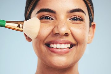 Image showing Portrait, woman and smile with makeup brush in studio, apply foundation and glow on blue background. Face of happy young model with aesthetic cosmetics, skincare tools and beauty powder for self care