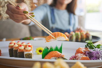 Image showing Hands, chopsticks and woman with sushi in restaurant, fine dining and eating in cafe store. Salmon, stick and person on fish, meat and tempura food in plate for lunch, brunch and healthy seafood meal