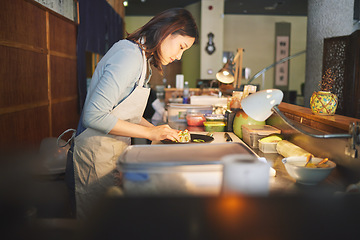 Image showing Chinese food, chef and an asian woman in a sushi restaurant to serve a traditional meal for nutrition. Kitchen, cooking or preparation with a happy young employee in an eatery for fine dining cuisine
