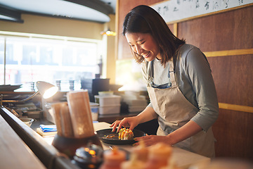 Image showing Sushi, restaurant worker and woman with smile from food and Asian meal in a kitchen. Happy, female waiter or chef working with fish and rice for lunch order with cooking in Japanese bar with service