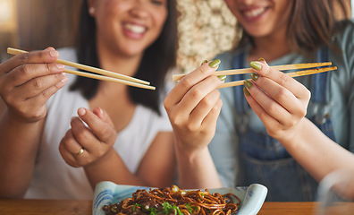 Image showing Chopsticks, restaurant and friends hands with noodles and Asian cuisine at a cafe. Happy, hungry women and plate of food at a Japanese bar with friendship, smile and bonding from meal at a table