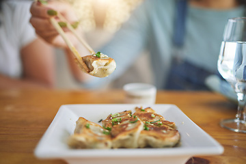 Image showing Table, plate and chopsticks with a dumpling at a restaurant for food, Asian culture or fine dining. Health, hungry and a person with dinner, eating lunch or enjoying a fried dish or cuisine at a cafe