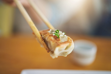 Image showing Closeup, protein and chopsticks with dumpling at a restaurant for food, Asian culture or fine dining. Health, hungry and person with dinner, eating lunch or enjoying a fried dish or cuisine at a cafe