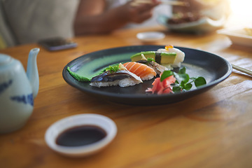 Image showing Sushi, food and chopsticks in a chinese restaurant closeup for fine dining or traditional cuisine. Salmon, menu and seafood with an asian dish on a table in a local eatery for hunger or nutrition