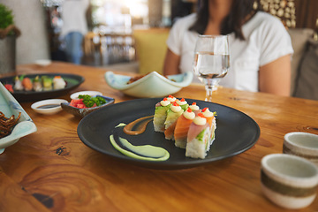 Image showing Table, eating and people with sushi at a restaurant for fish, Chinese food or hungry. Closeup, plate and a person with seafood, lunch or dinner at a fine dining cafe for Asian cuisine or health